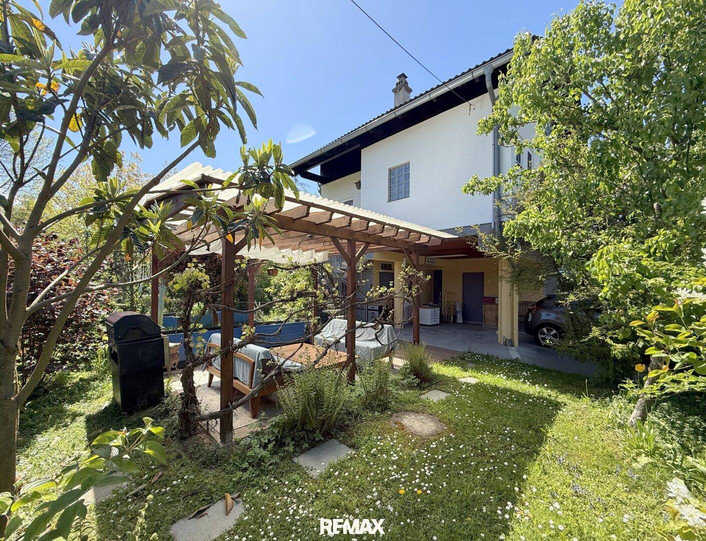 Charmantes Haus mit Garten, überdachter Pergola und viel Grünfläche im Freien.