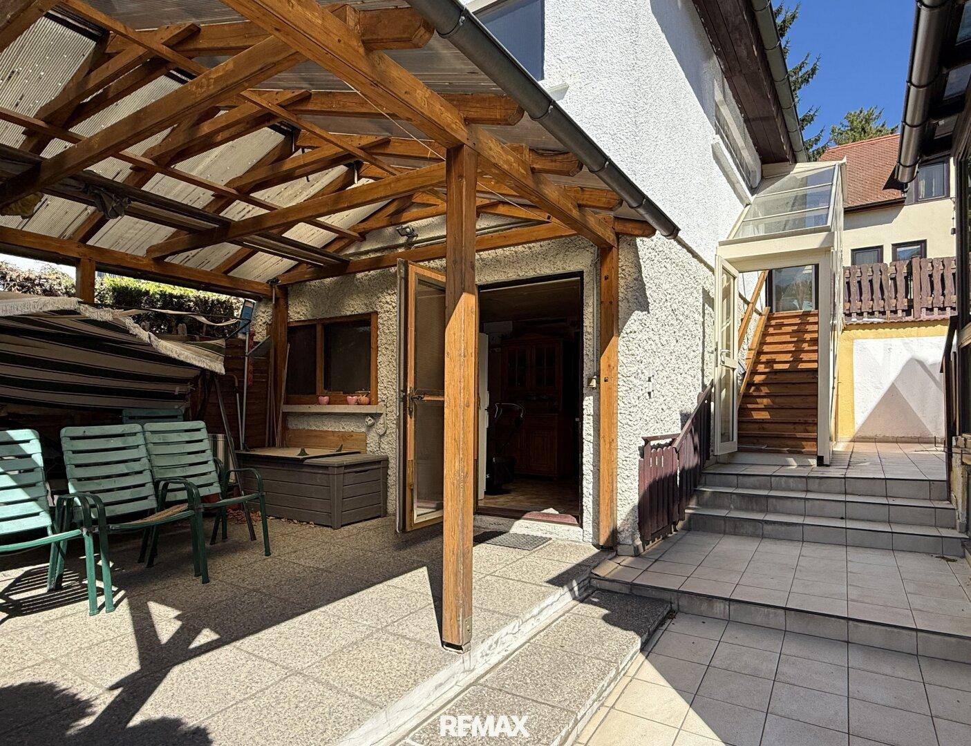 Überdachte Terrasse mit Sitzgelegenheiten und Zugang zum Haus.