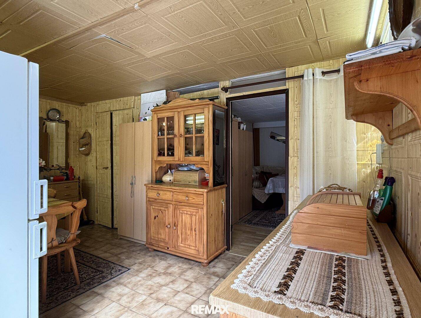 Rustikaler Mehrzweckraum mit Holzverkleidung, Schränken und kleinem Essbereich.