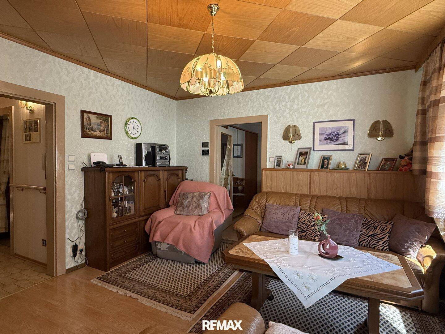 Wohnzimmer mit traditioneller Einrichtung, Holzdecke und bequemen Ledersofas.