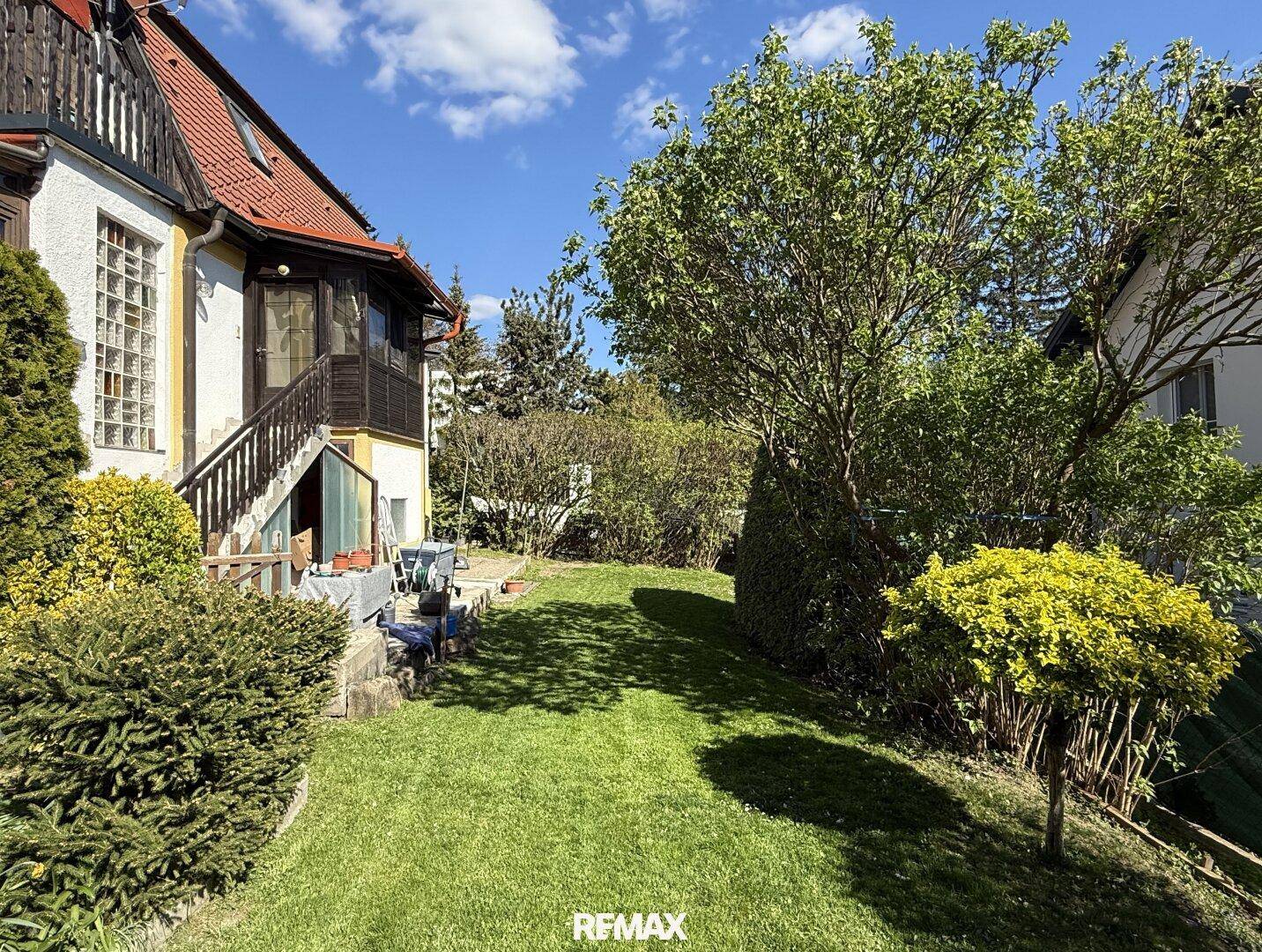 Großer, gepflegter Garten mit Rasenfläche und Bäumen hinter dem Haus.