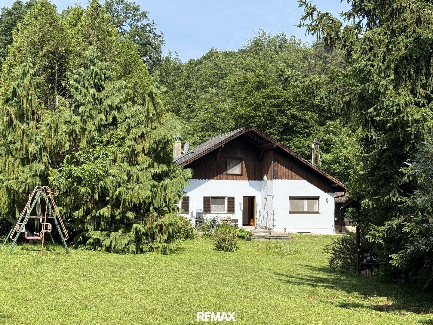 Weitläufiger Gartenbereich mit altem Baumbestand und Kinderspielgerät im Grünen.