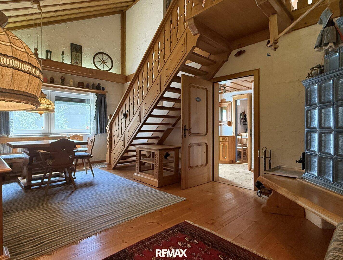 Gemütlicher Wohn- und Essbereich im alpinen Stil mit Holzboden und traditionellem Kachelofen.