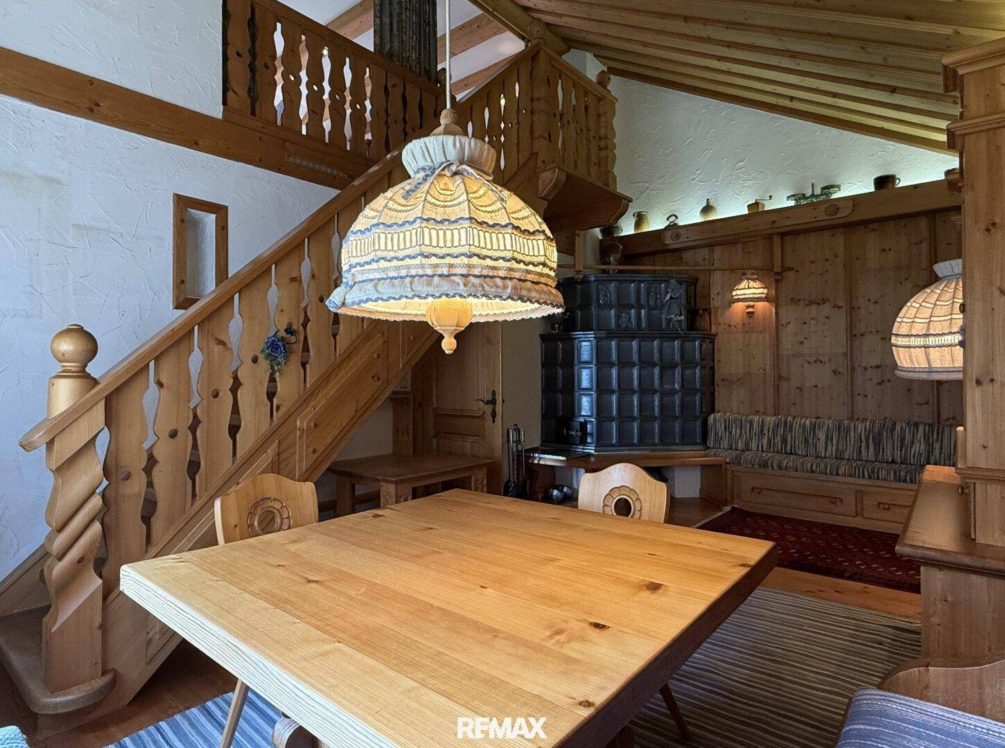 Rustikaler Essbereich mit Holztisch, passenden Stühlen und Blick auf die Holztreppe.