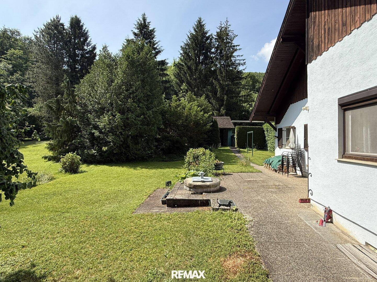 Gepflasterter Terrassenbereich neben dem Haus mit Blick auf den weitläufigen Garten.