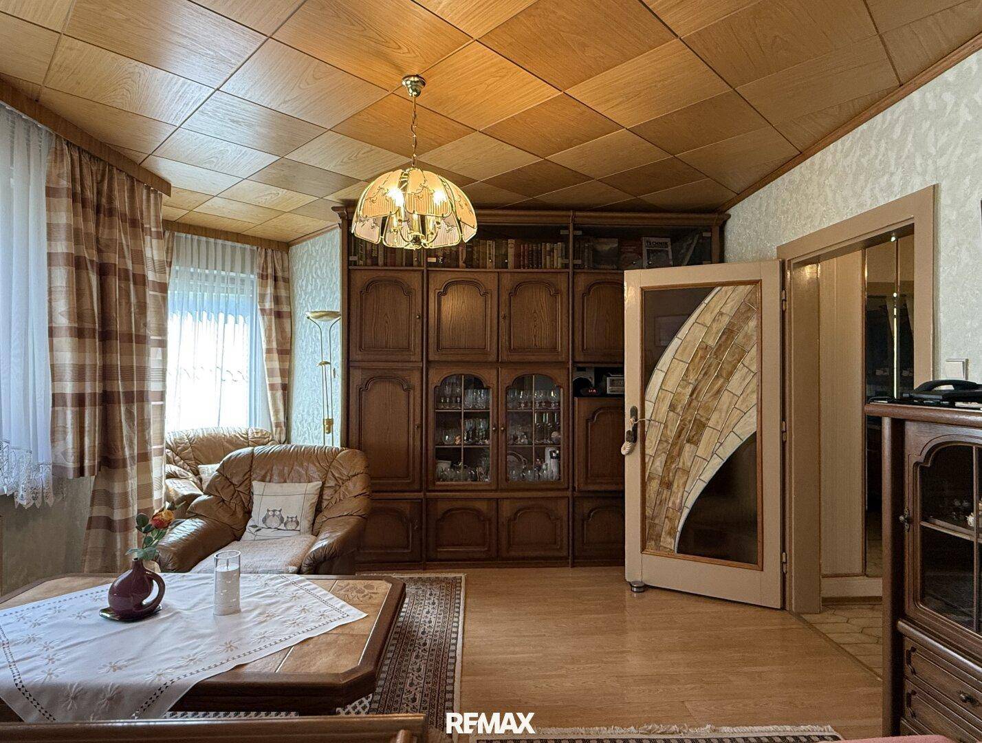 Geräumiges Wohnzimmer mit großer Holzschrankwand, Parkettboden und traditioneller Einrichtung.