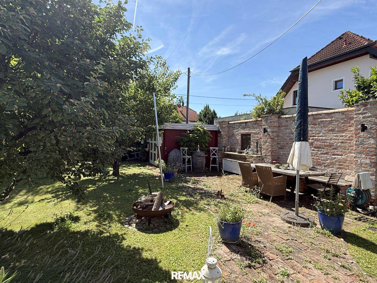 Gemütlicher Gartenbereich mit Sitzgelegenheiten, Grillplatz und Ziegelmauer.