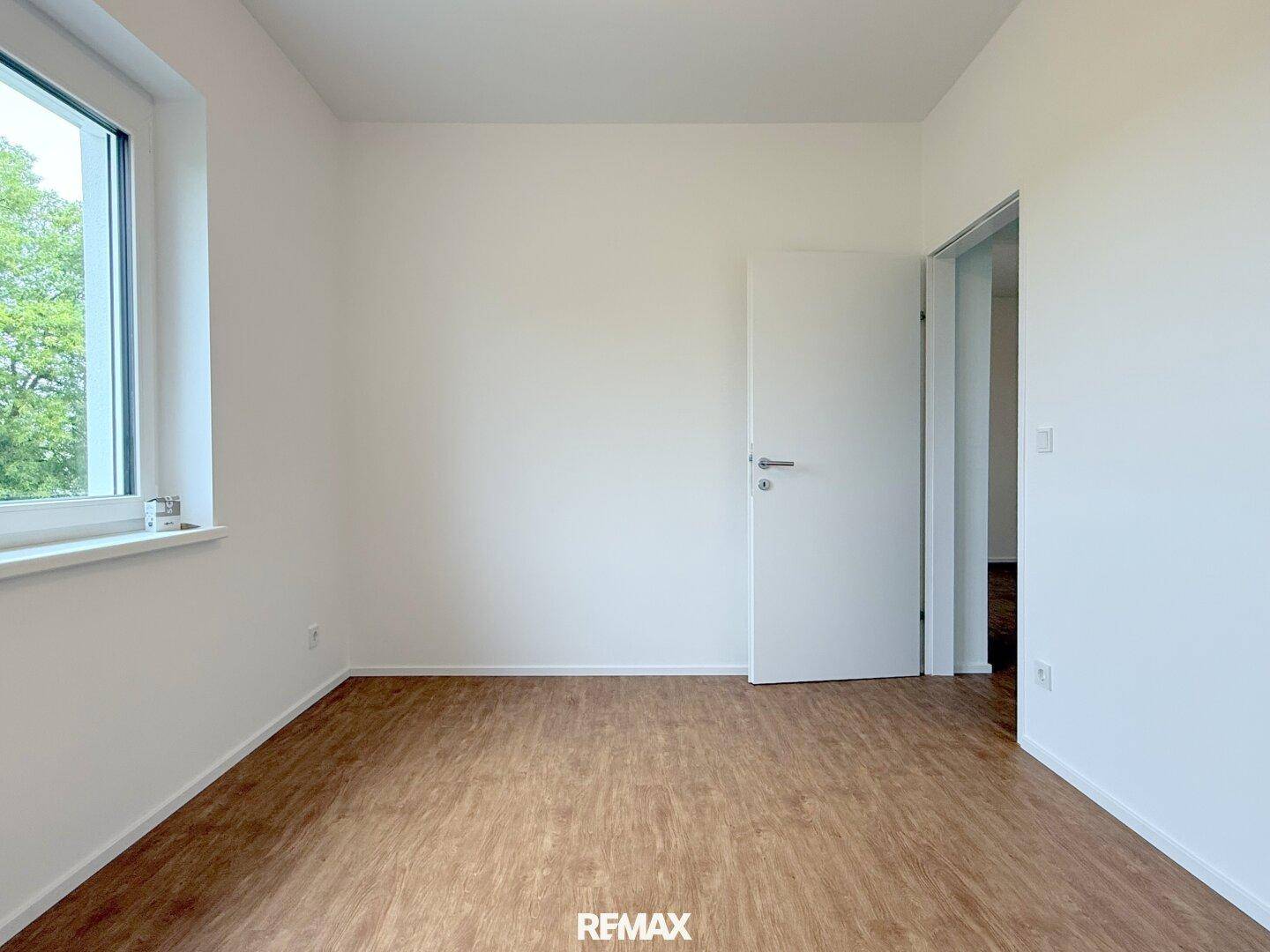 Freundliches Schlafzimmer mit Laminatboden und weiß gestrichenen Wänden, bereit zum Einrichten.