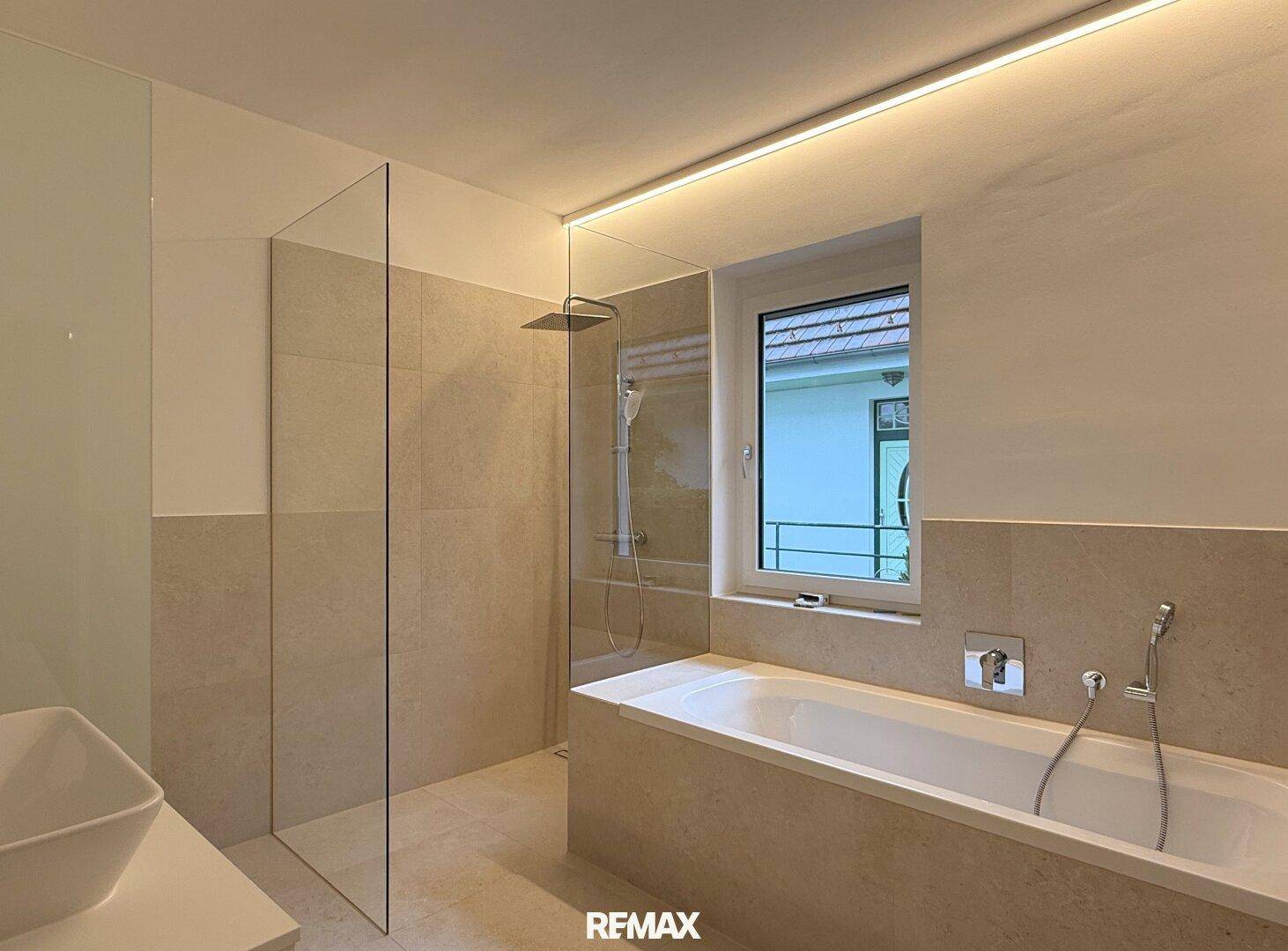 Modernes Badezimmer mit großer begehbarer Dusche, Badewanne und Fenster für Tageslicht.