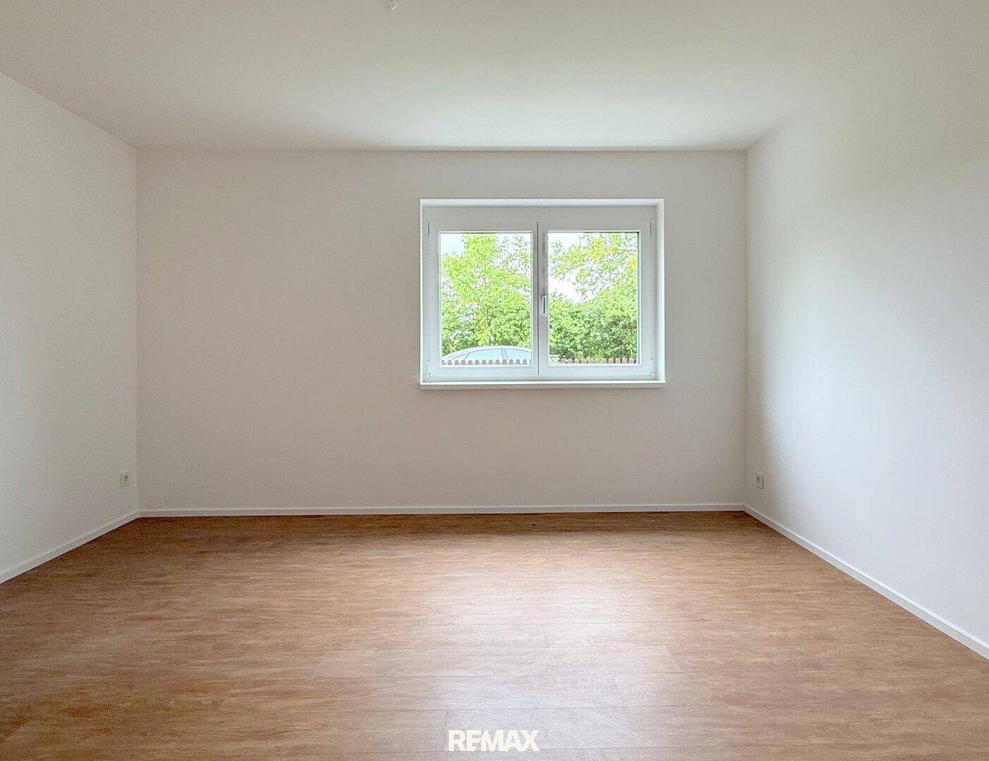 Geräumiges Schlafzimmer mit Laminatboden und großem Fenster, das viel Licht spendet.