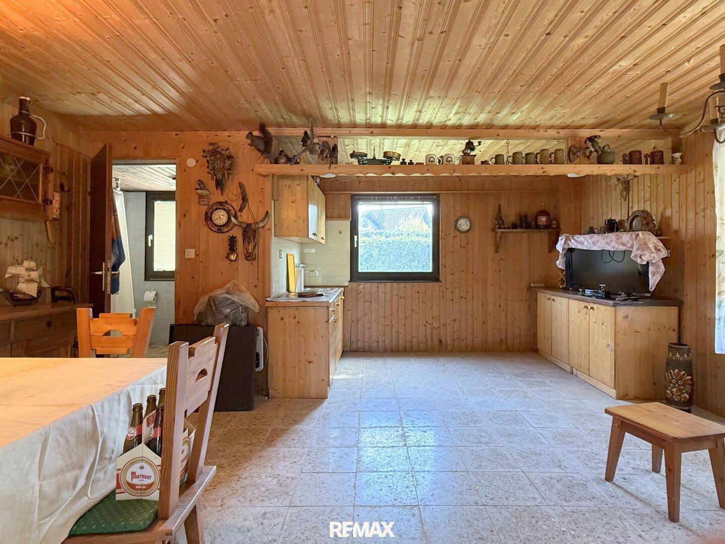 Rustikaler Wohnbereich mit Holztäfelung, kleiner Küchenzeile und traditioneller Dekoration.