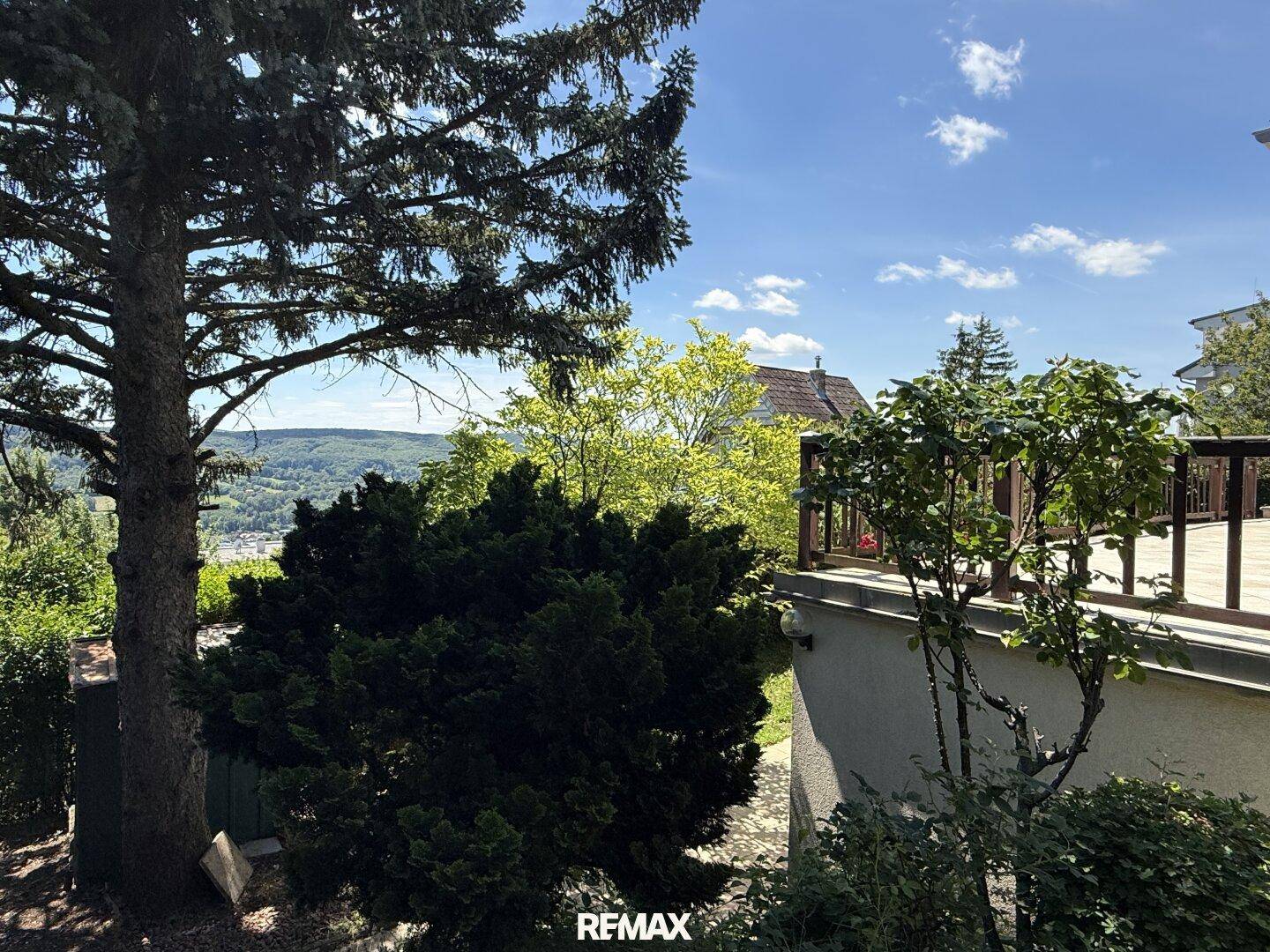 Blick auf den Garten und die obere Terrasse des Hauses mit weitreichender Aussicht.