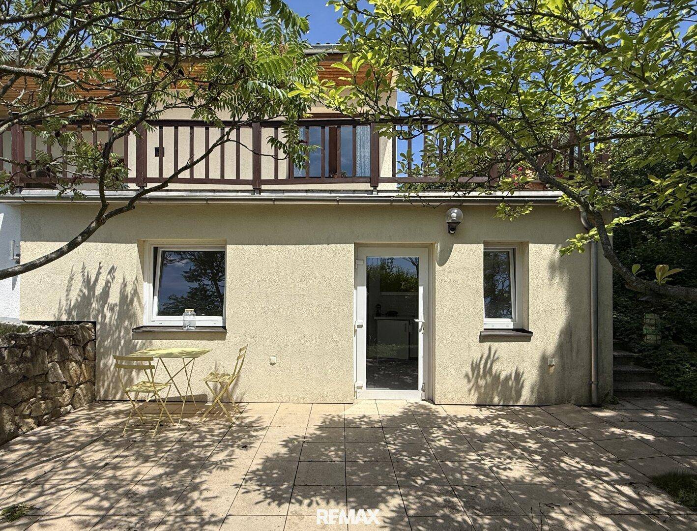 Untere Ebene des Hauses mit einer gepflasterten Terrasse und Sitzgelegenheiten im Freien.