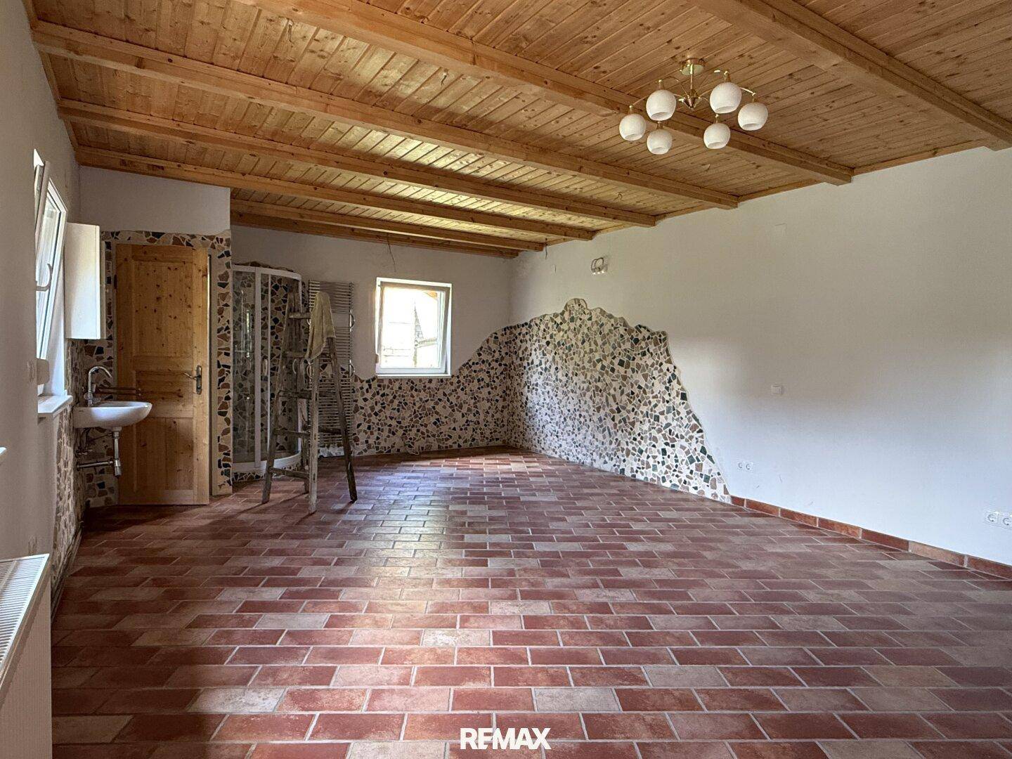 Rustikaler Raum mit Terrakottafliesen, Holzdecke und einer Duschkabine in der Ecke, bereit zur Gestaltung.
