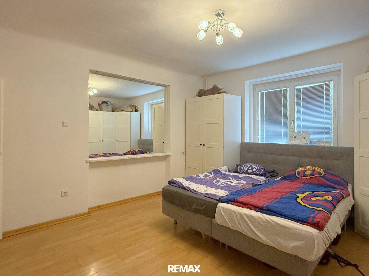 Kinderzimmer oder Gästezimmer mit zwei Betten, Holzboden und weißem Kleiderschrank.