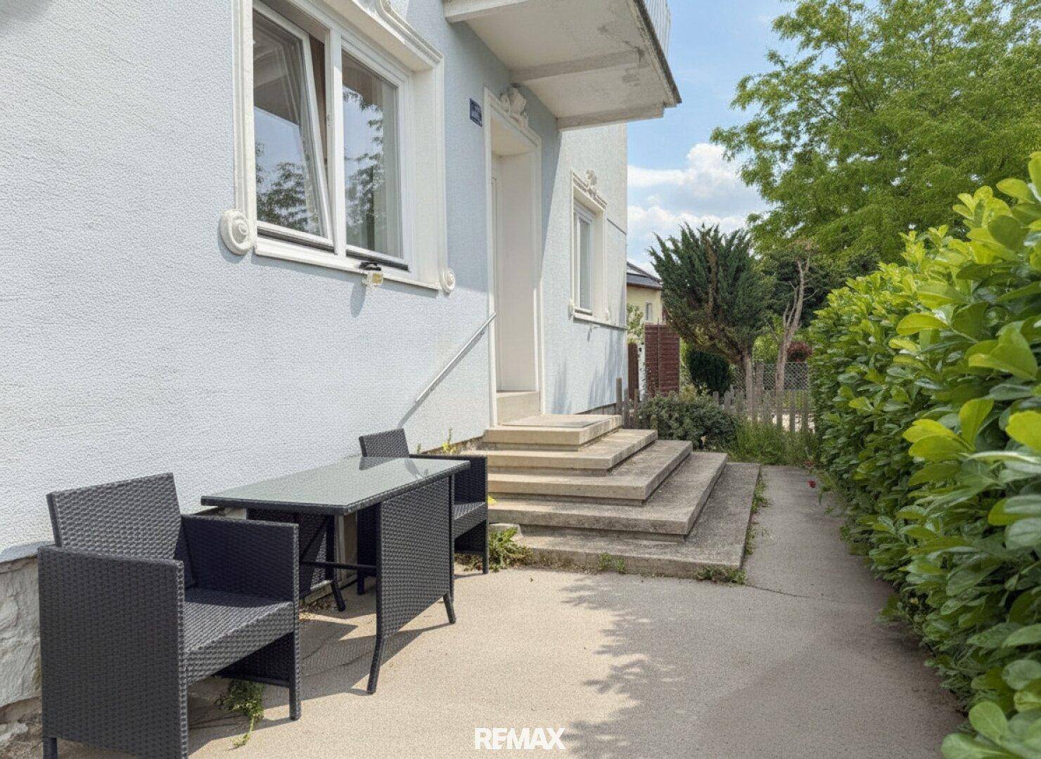 Kleiner gepflasterter Bereich vor dem Hauseingang mit Outdoor-Sitzgelegenheiten.