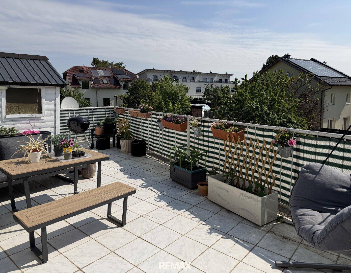 Geräumige Dachterrasse mit Fliesenboden, Grillbereich und Blick auf die Umgebung.