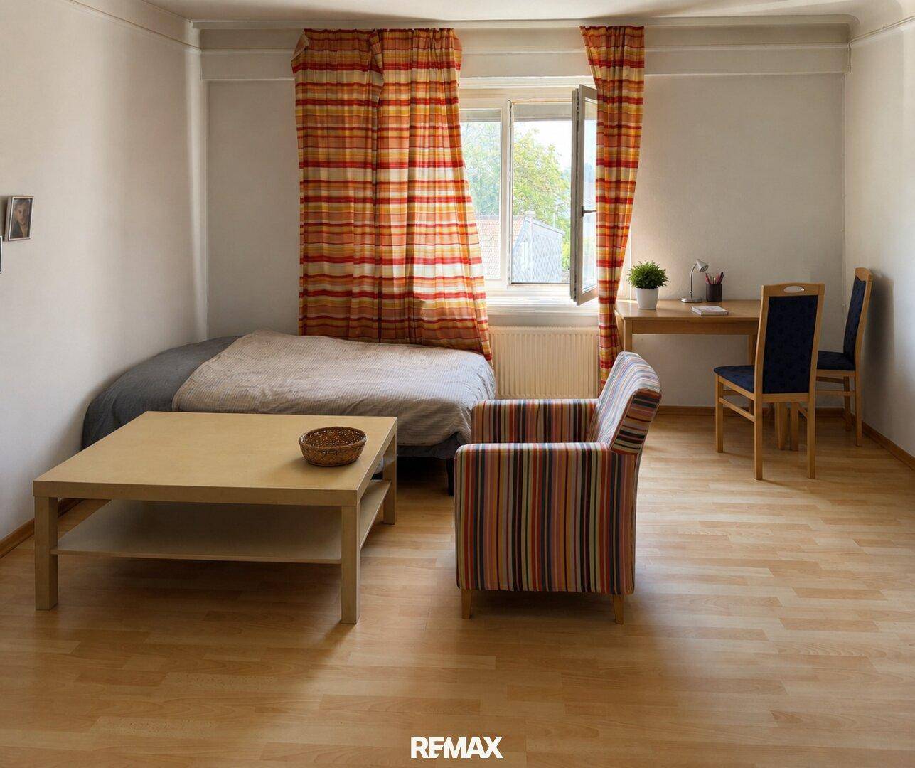 Helles Schlafzimmer oder Gästezimmer mit Einzelbett, Sessel und Holzboden.
