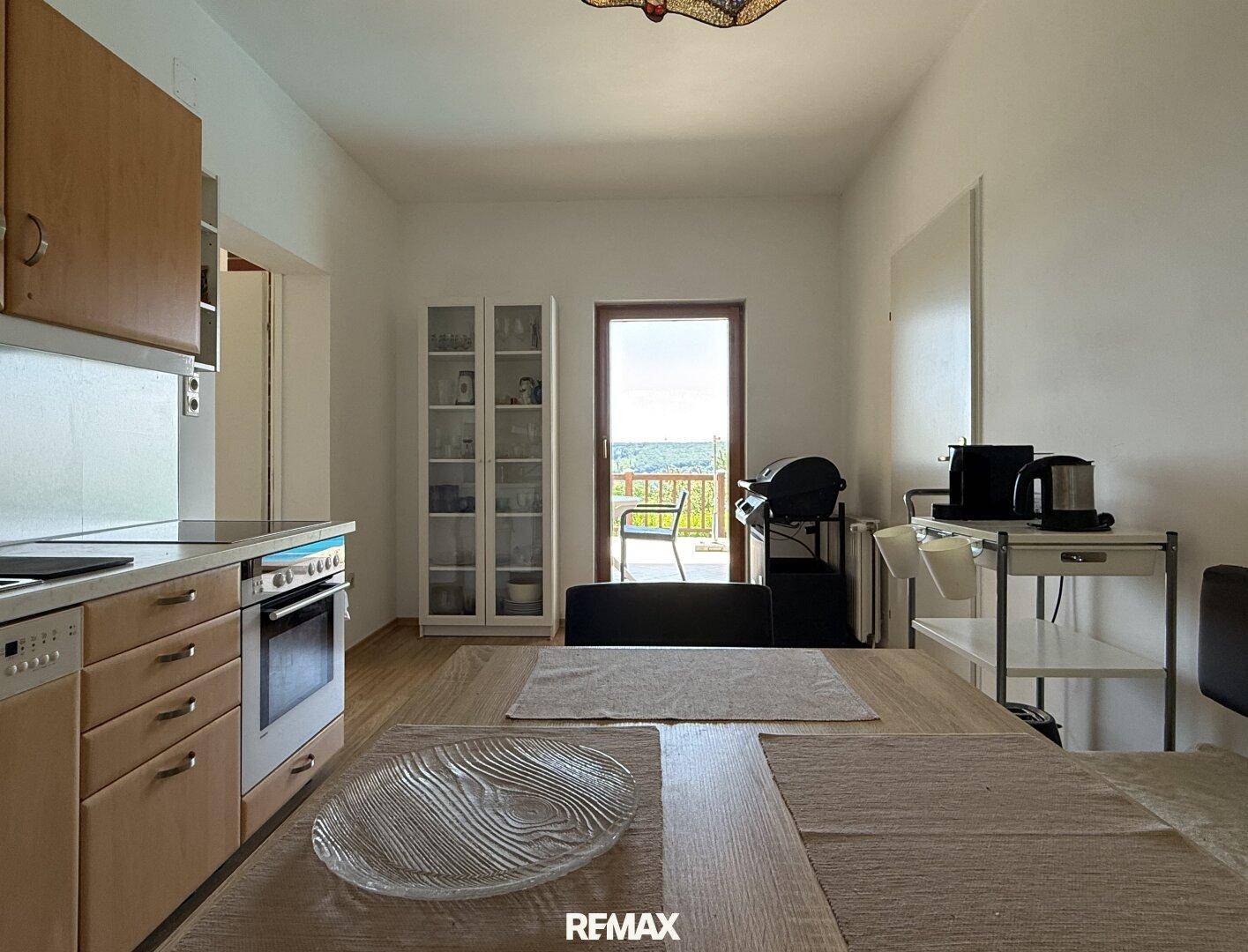 Helle Küche mit Essbereich und Zugang zu einem Balkon mit schöner Aussicht.