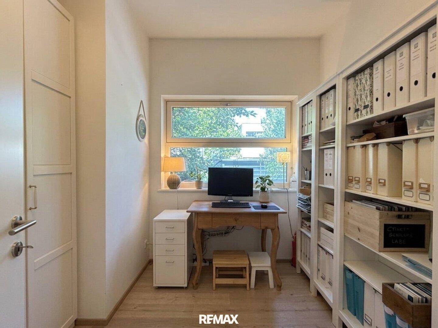 Helles Arbeitszimmer mit Schreibtisch, Bücherregalen und Blick ins Grüne.