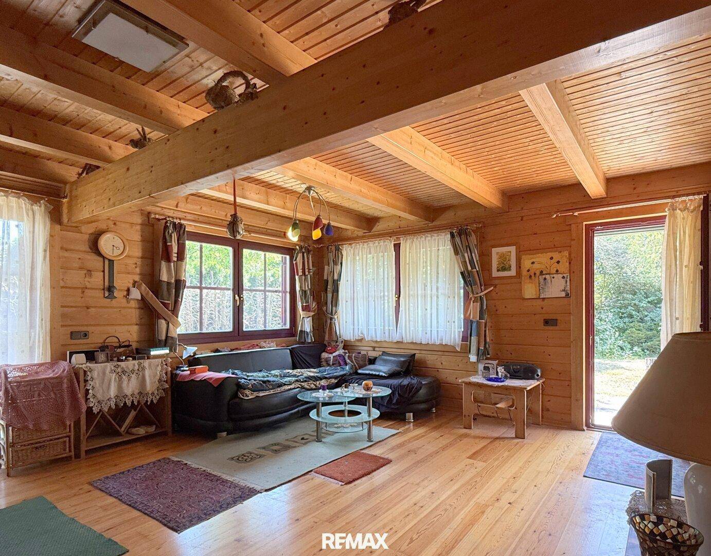 Helles Wohnzimmer mit Holzboden, bequemer Couch und Zugang zum Außenbereich.