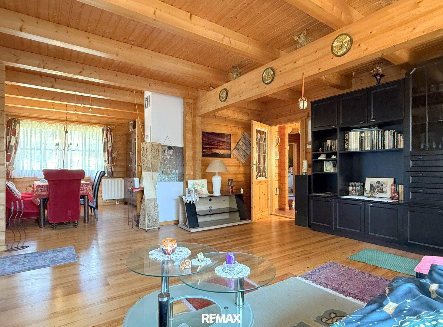 Offener Wohn- und Essbereich mit Holzboden, sichtbaren Balken und traditioneller Einrichtung.
