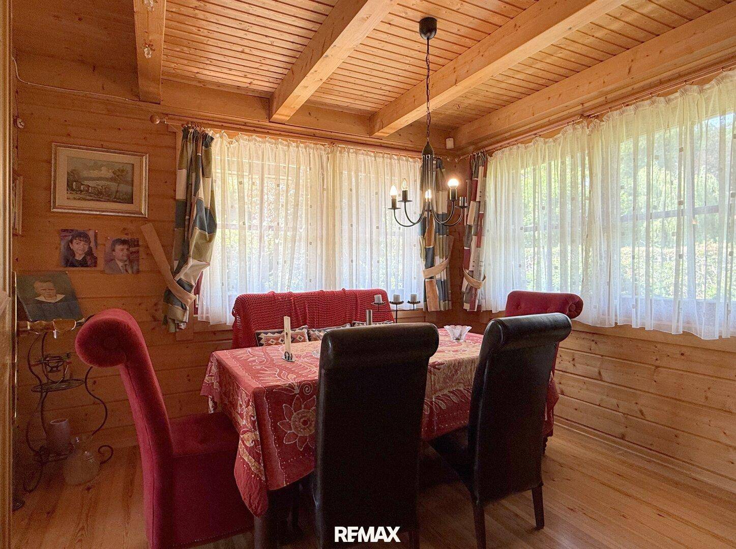 Gemütlicher Essbereich mit Holzwänden, großem Fenster und traditionellem Kronleuchter.