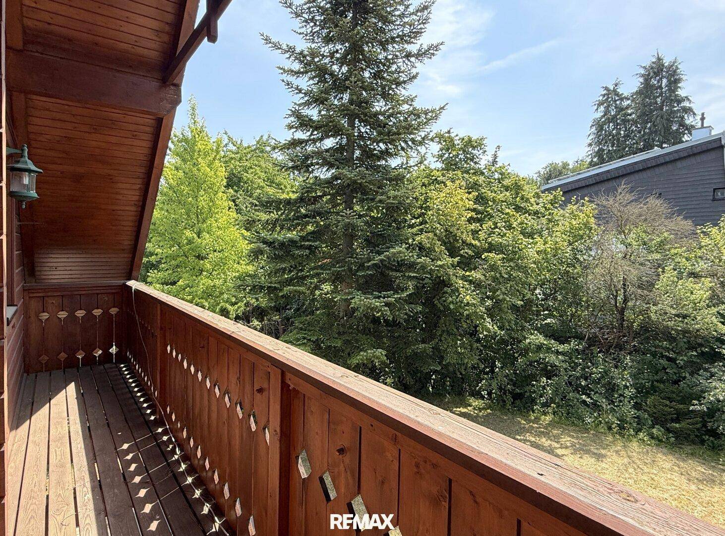 Hölzerner Balkon mit Blick auf die umliegende grüne Landschaft und Bäume.