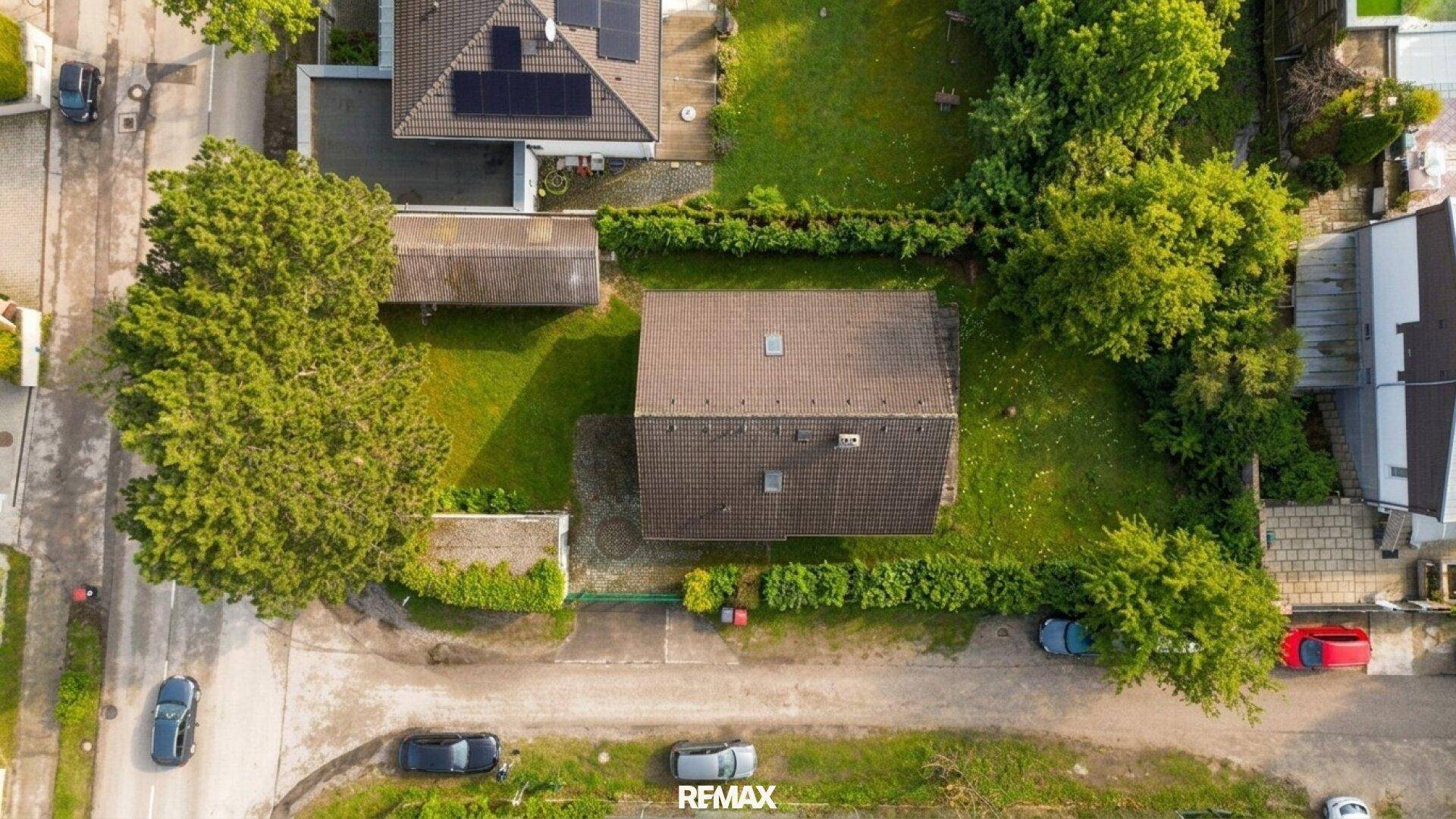 Vogelperspektive des Grundstücks mit Blockhaus, Garten und umliegender Bebauung.