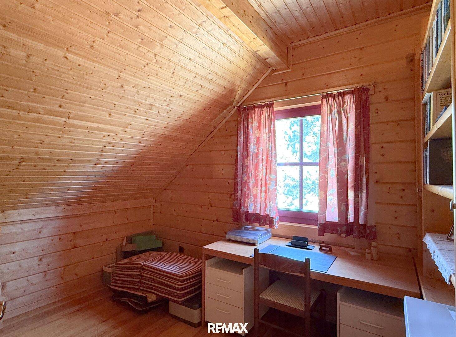 Helles Dachzimmer, eingerichtet als Arbeitsbereich mit Holzwänden und Schreibtisch.