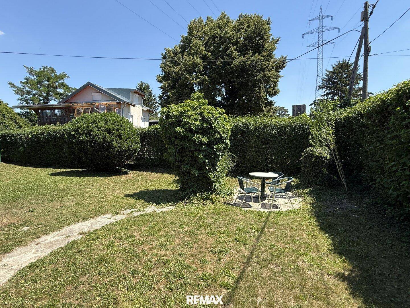 Gepflegter Gartenbereich mit Sitzgelegenheit und hohen Hecken als natürlichen Sichtschutz.
