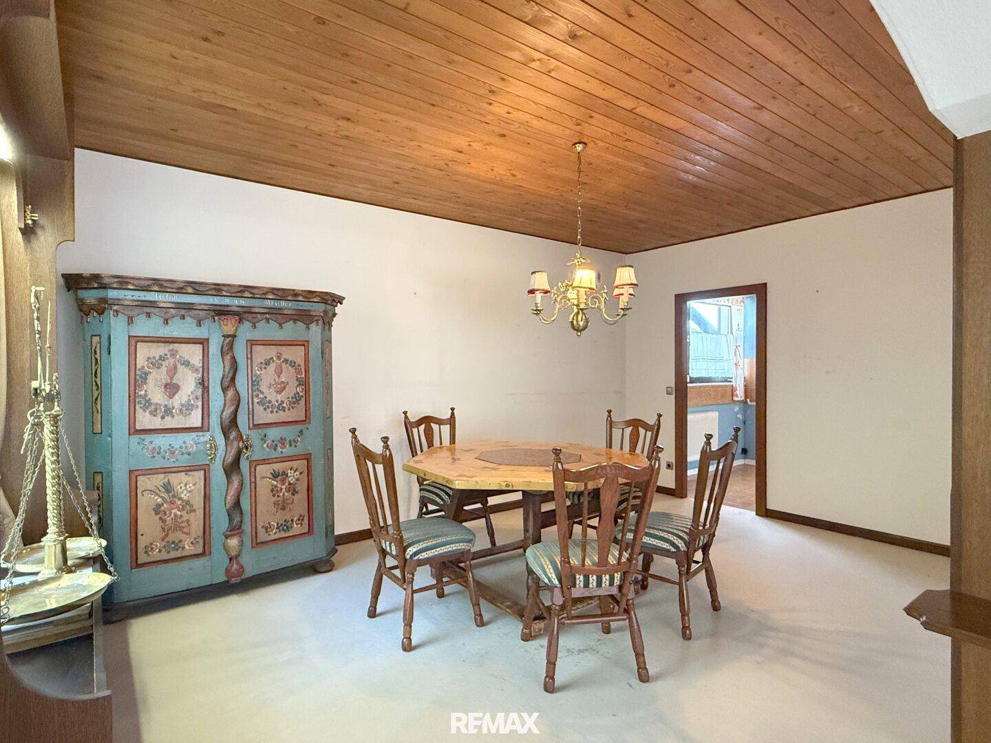 Esszimmer mit Holzdecke, Teppichboden und traditionellen Holzmöbeln.