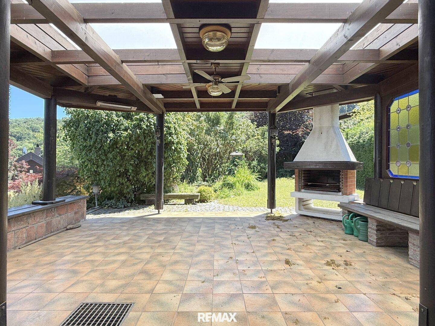 Überdachte Terrasse mit Fliesenboden, Deckenventilator und gemauertem Grillplatz.