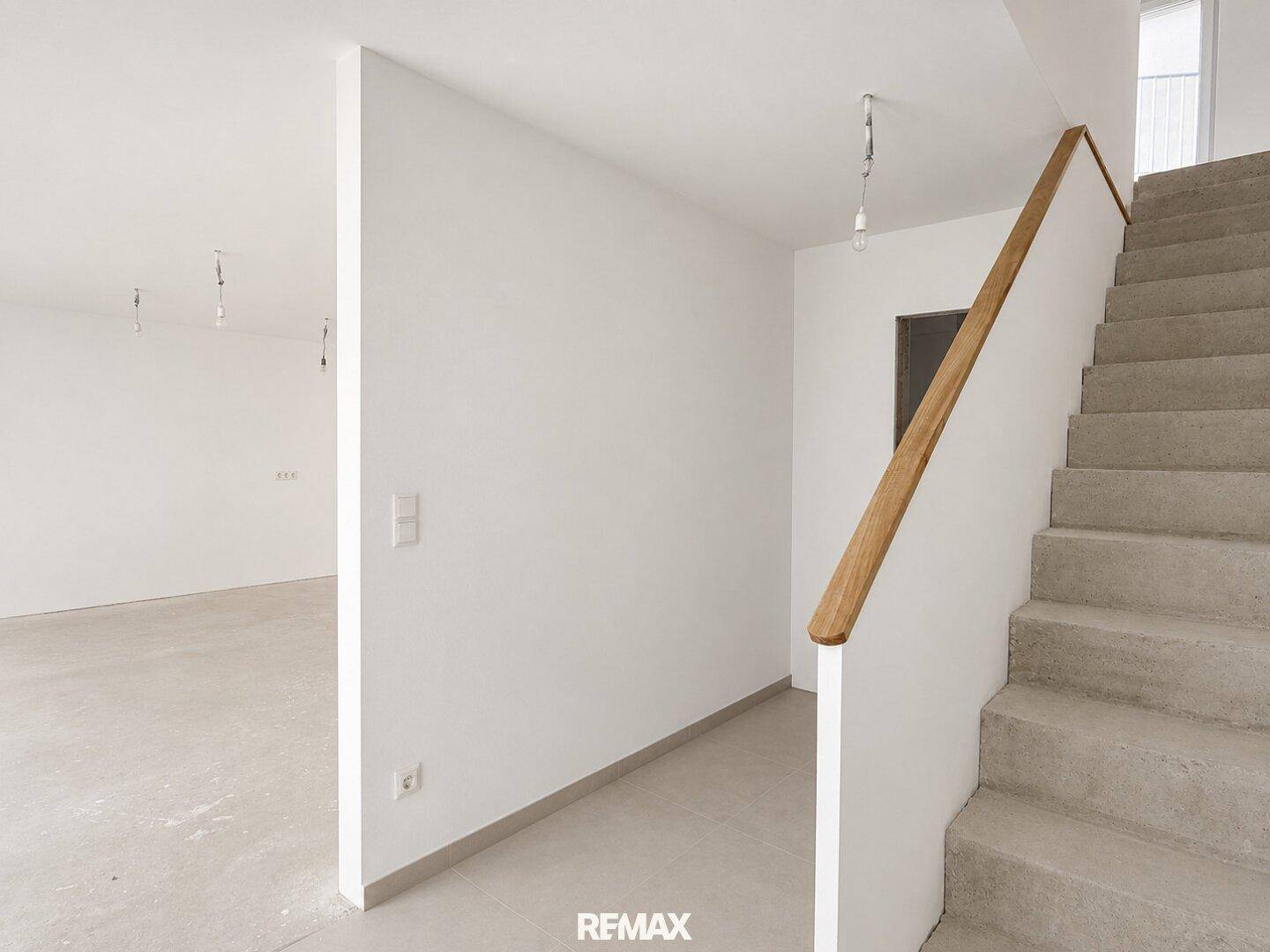 Heller Eingangsbereich mit Treppe und Rohbauzustand, bereit für individuelle Gestaltung.