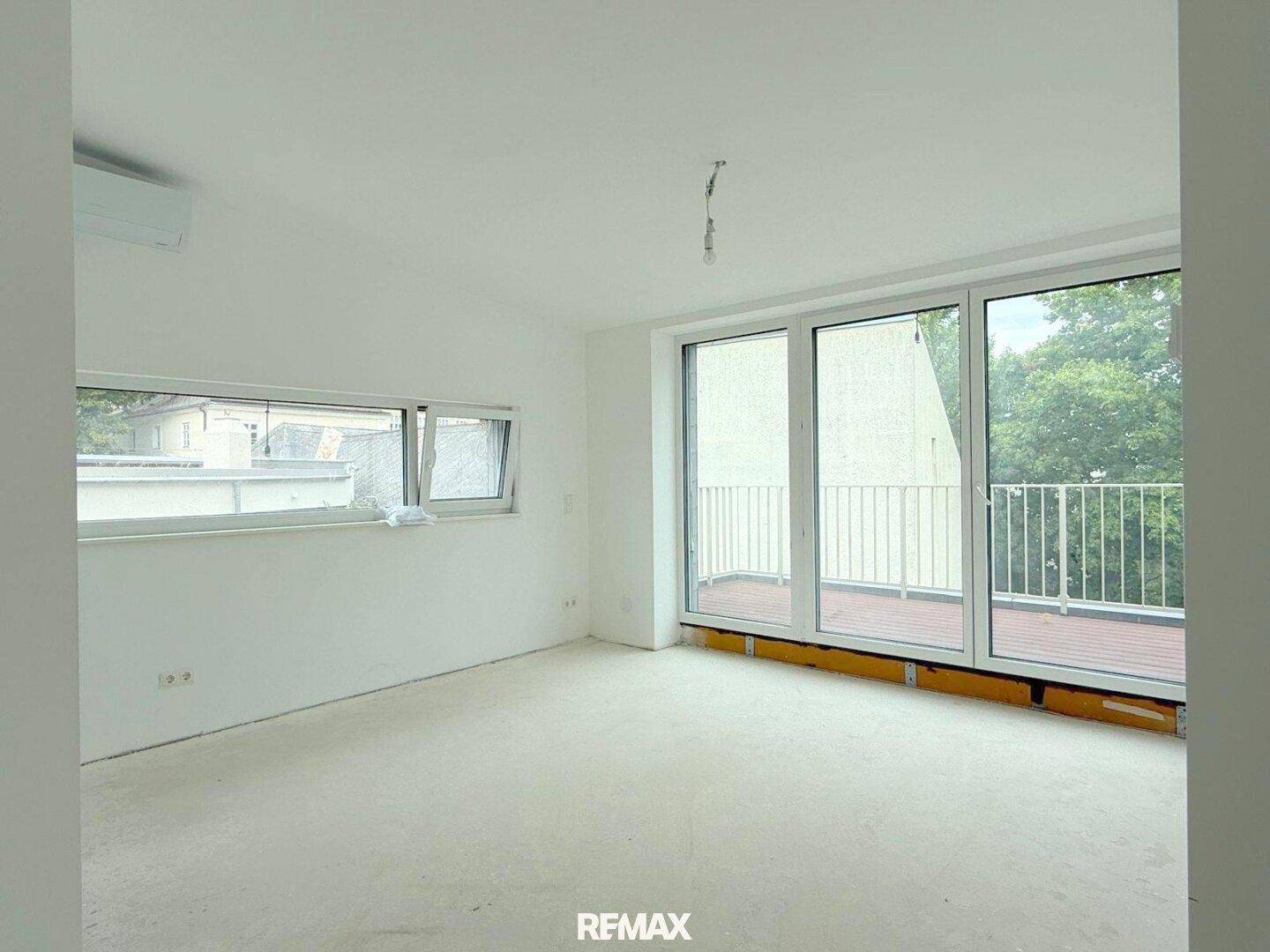 Geräumiges Schlafzimmer im Rohbau mit Balkonzugang und großen Fenstern.