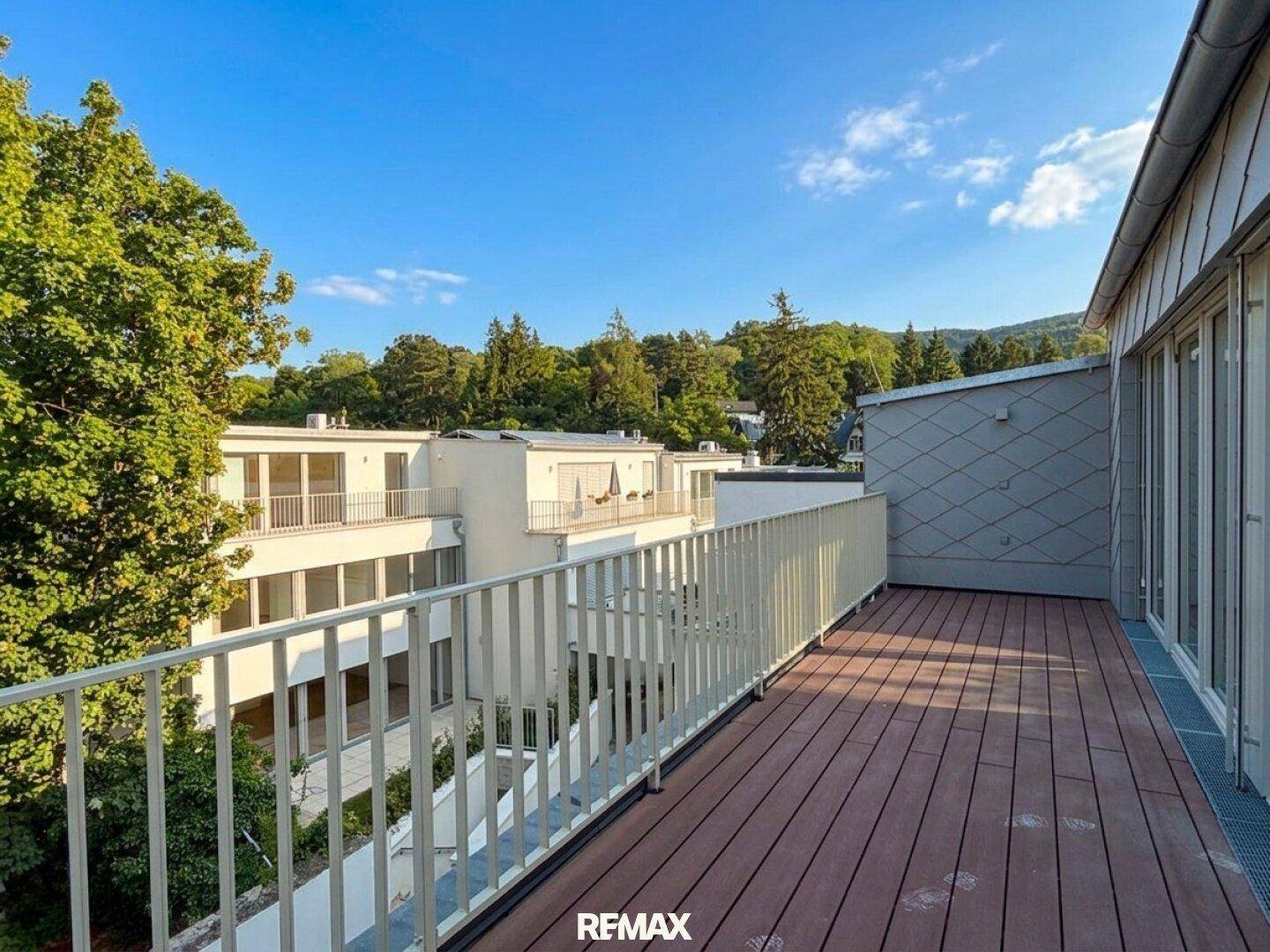 Großer Balkon mit Holzboden und weitem Blick über die moderne Wohnanlage.