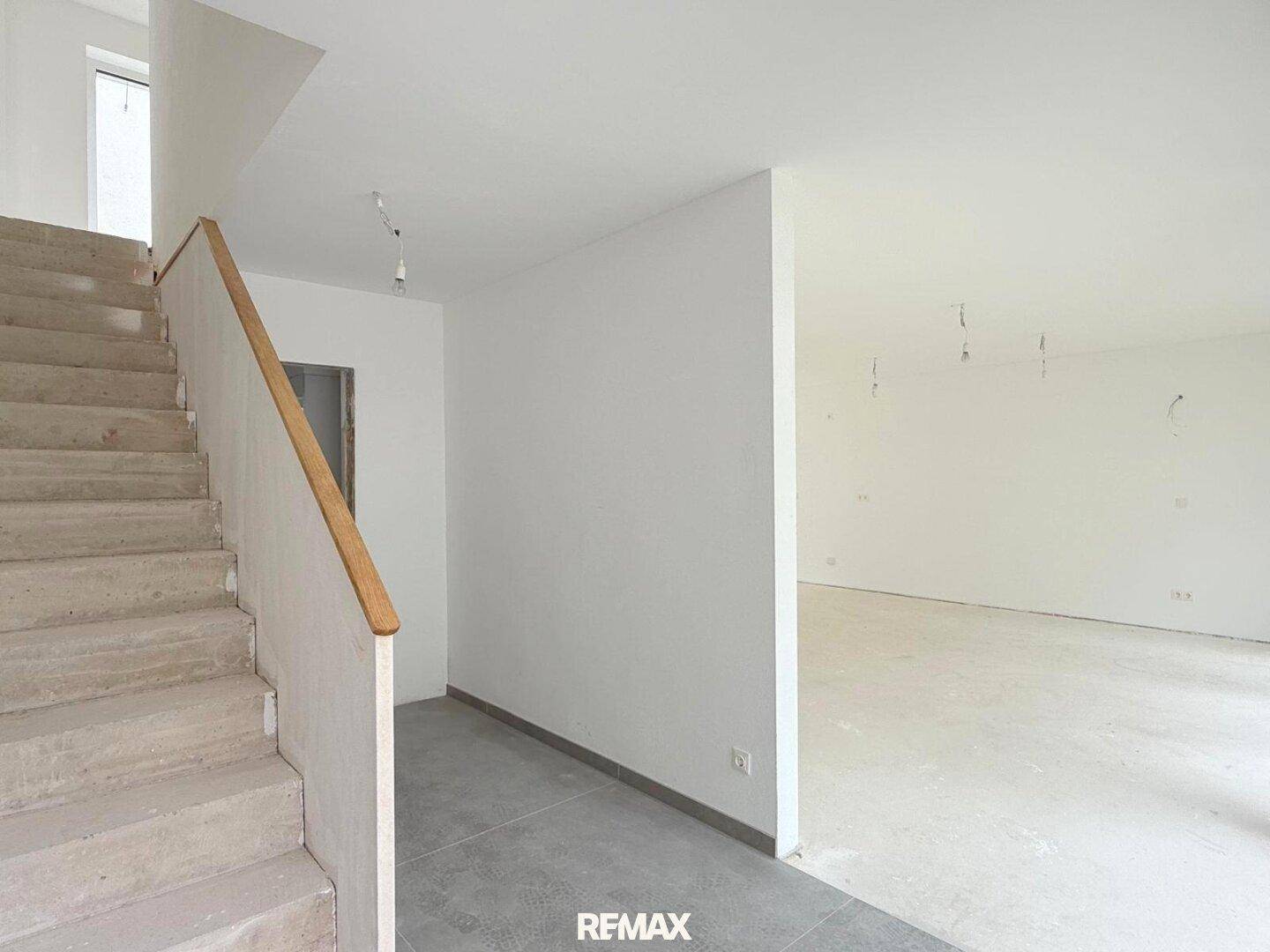 Unfertiger Flur mit Betontreppe und Fliesenboden, bereit für den weiteren Ausbau.