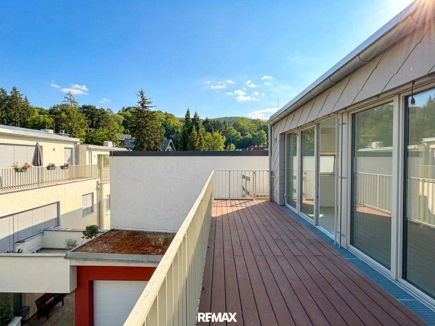 Großer Balkon mit Holzboden und Metallgeländer, bietet weite Aussicht auf die grüne Umgebung.