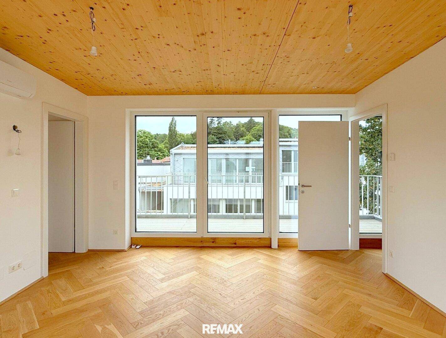 Helles Zimmer mit Holzdecke, Eichenparkett und bodentiefen Fenstern mit Balkonzugang.