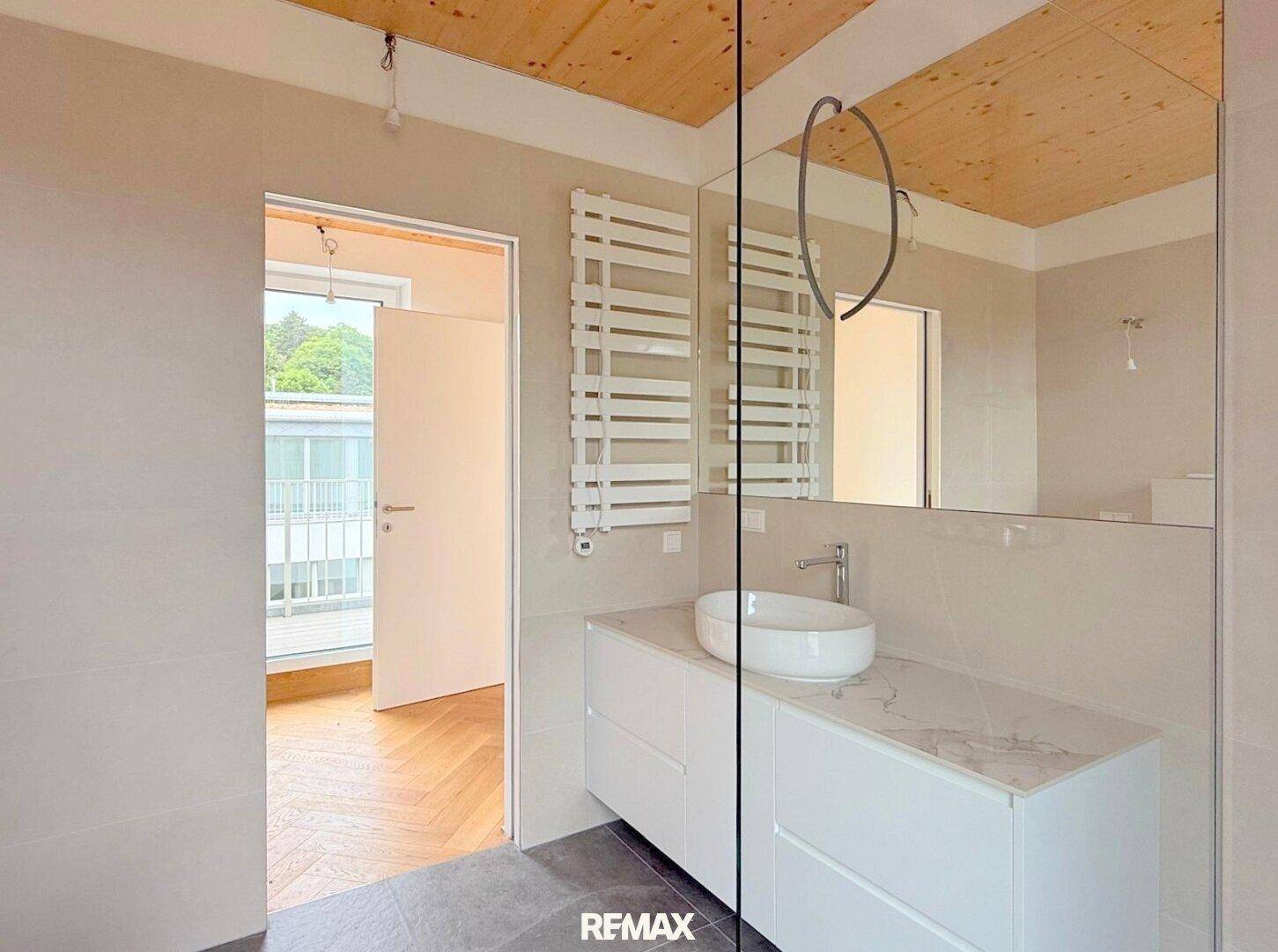 Helles Badezimmer mit Holzdecke, modernem Waschtisch, großem Spiegel und beheiztem Handtuchhalter.