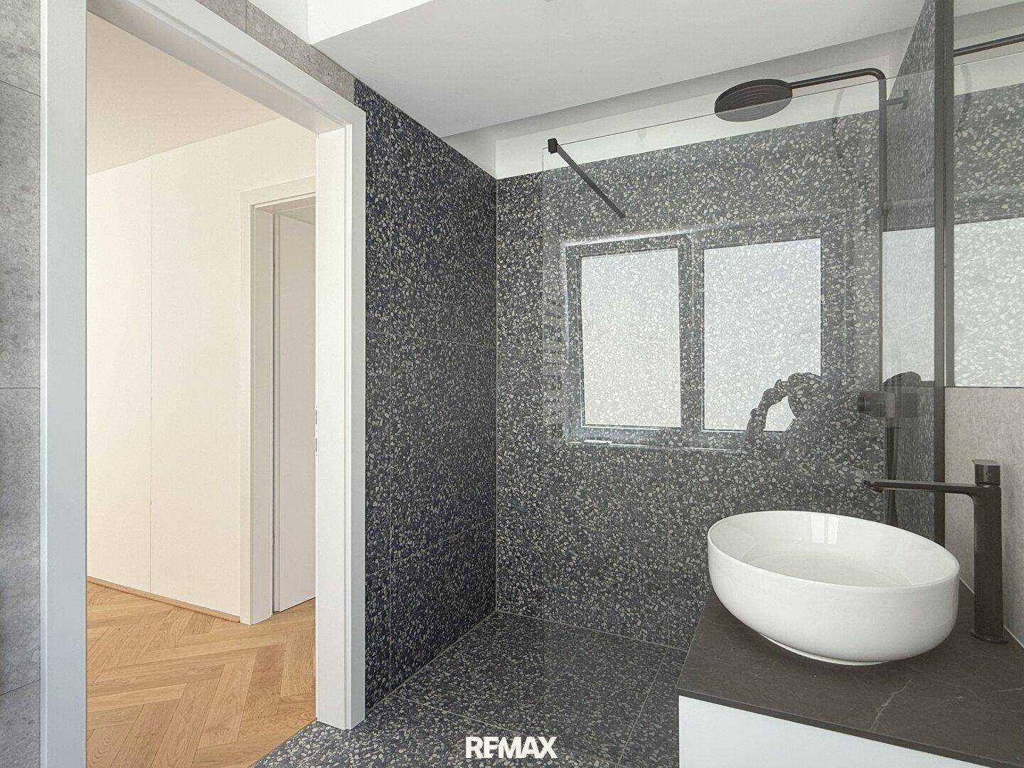 Elegantes Badezimmer mit großer begehbarer Dusche und modernem Aufsatzwaschbecken.