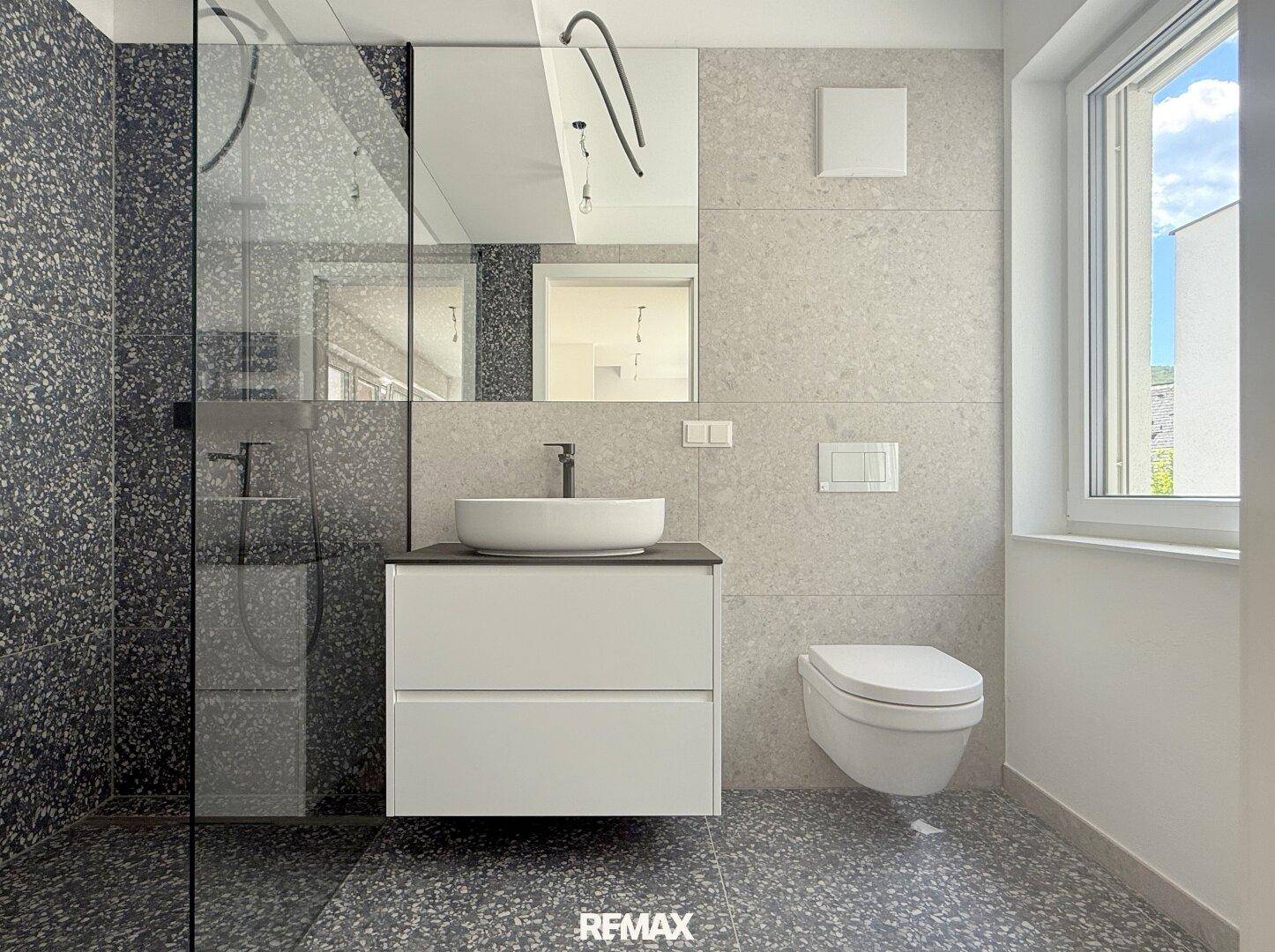 Modernes Badezimmer mit begehbarer Dusche, stilvollem Waschbecken und Wand-WC.