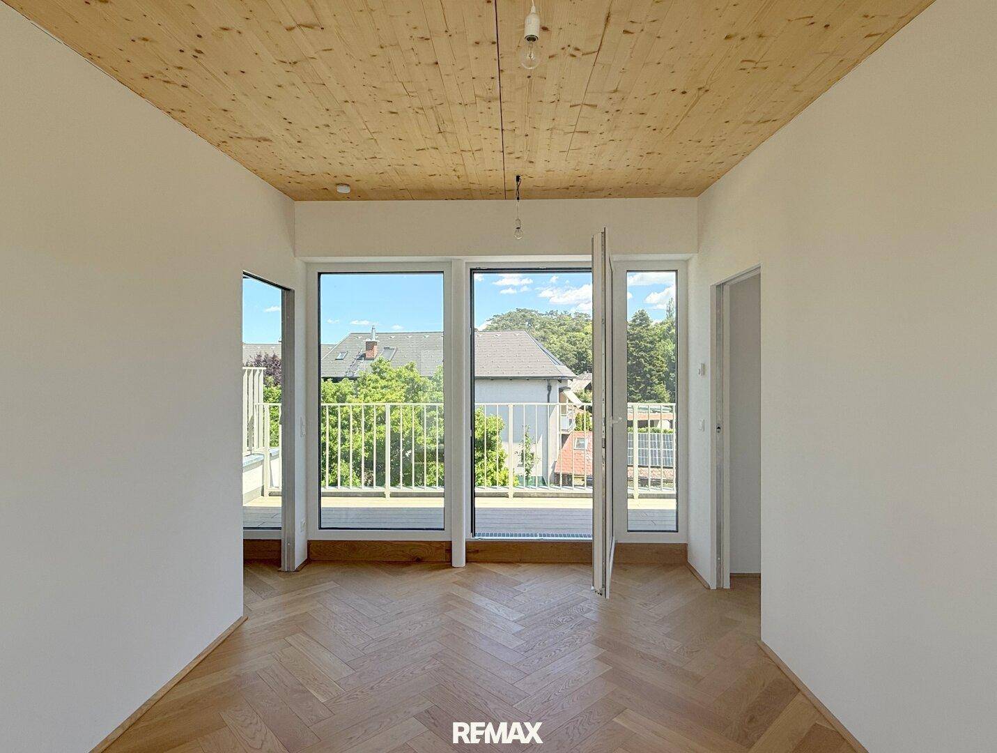 Helles Schlafzimmer mit Holzbalkendecke, Fischgrätparkett und offenem Zugang zum Balkon.