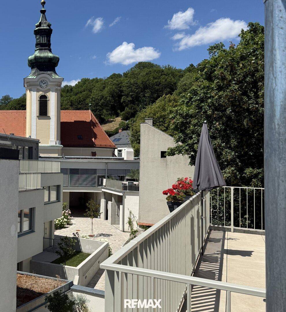 Balkon mit Blick auf einen historischen Kirchturm und die umliegende Bebauung.