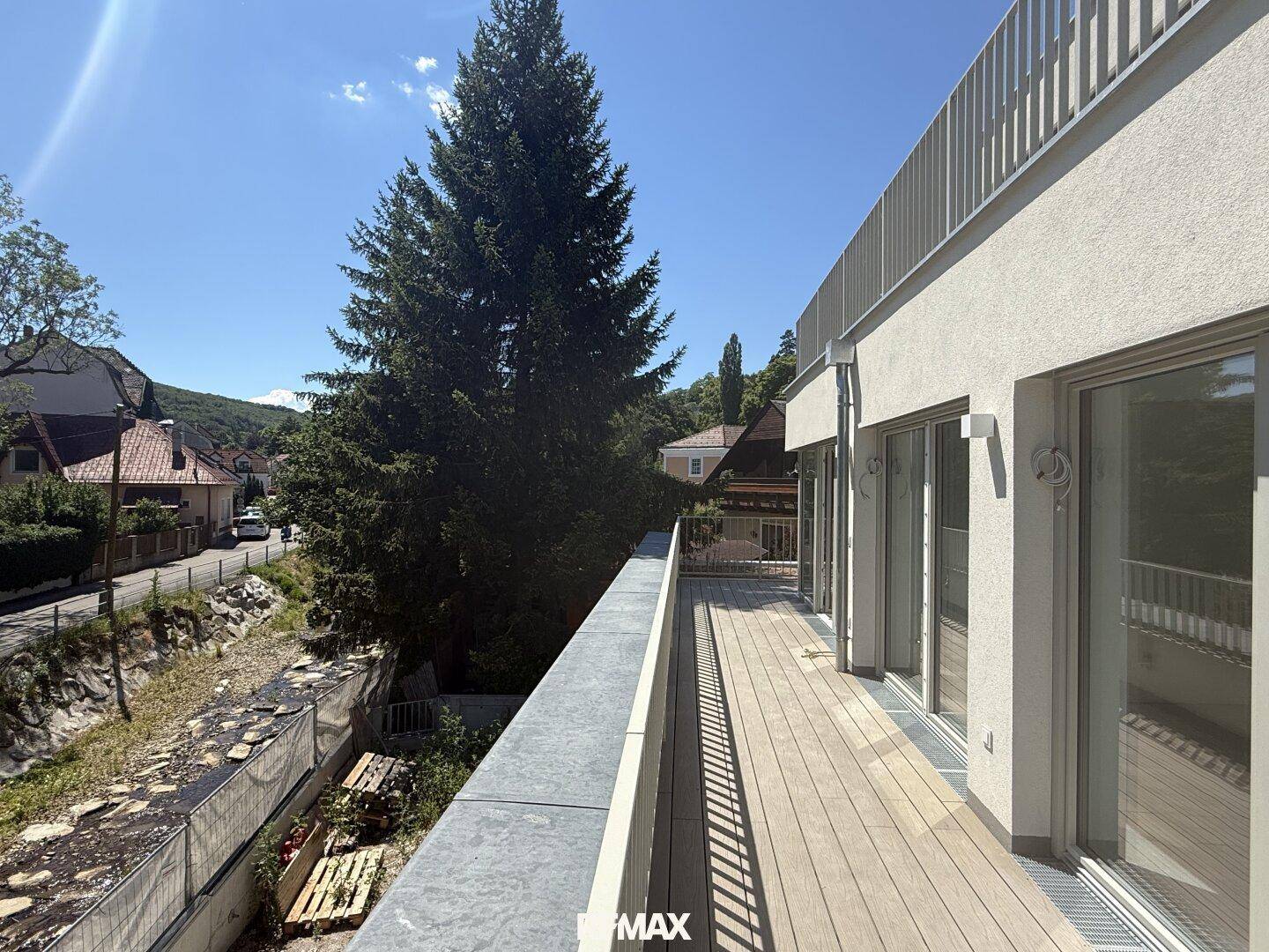 Langer Balkon mit Holzboden und Blick auf die umliegende Natur und den Bach.