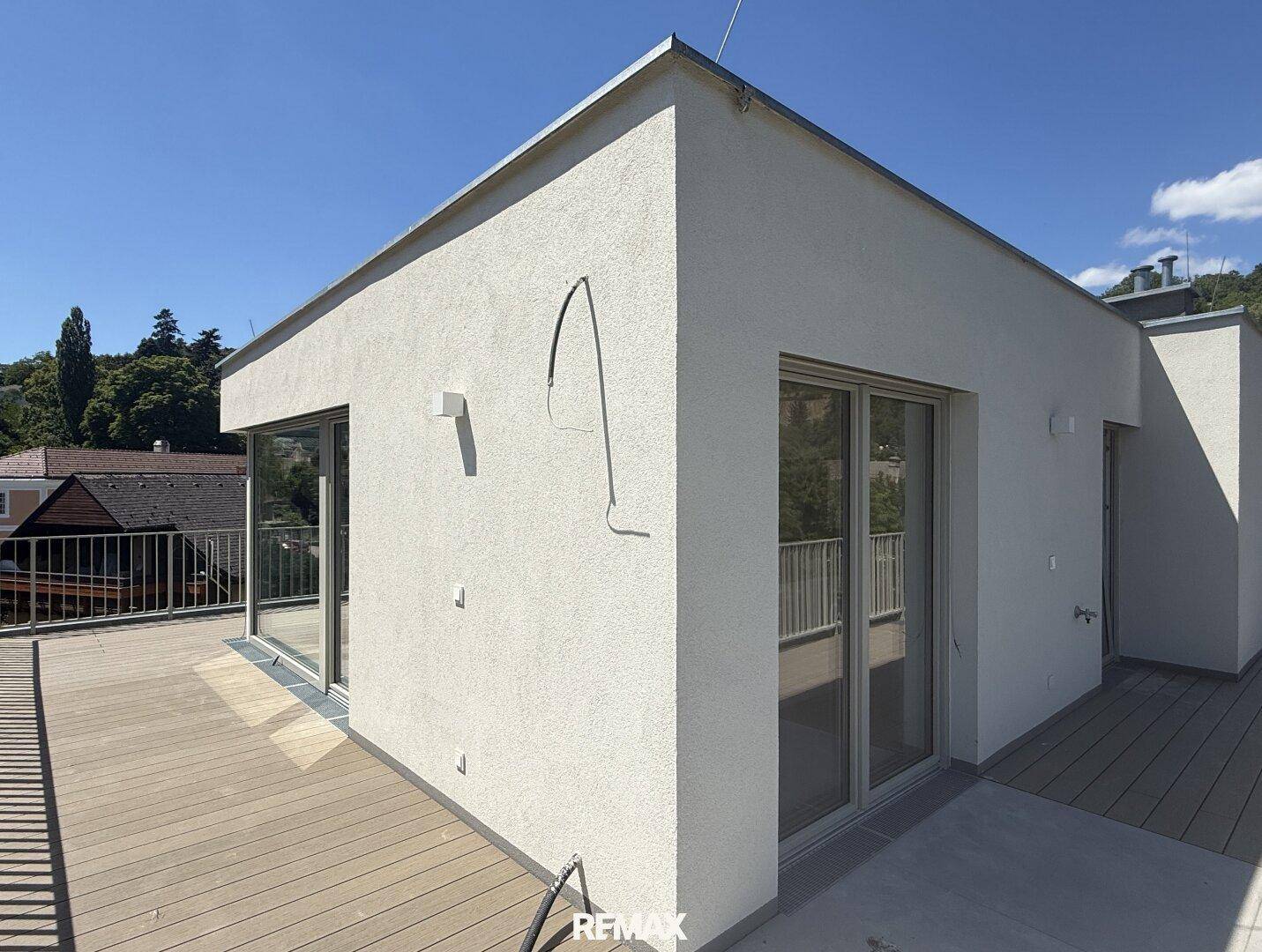 Geräumige Dachterrasse mit Holzboden und moderner Architektur des Gebäudes.