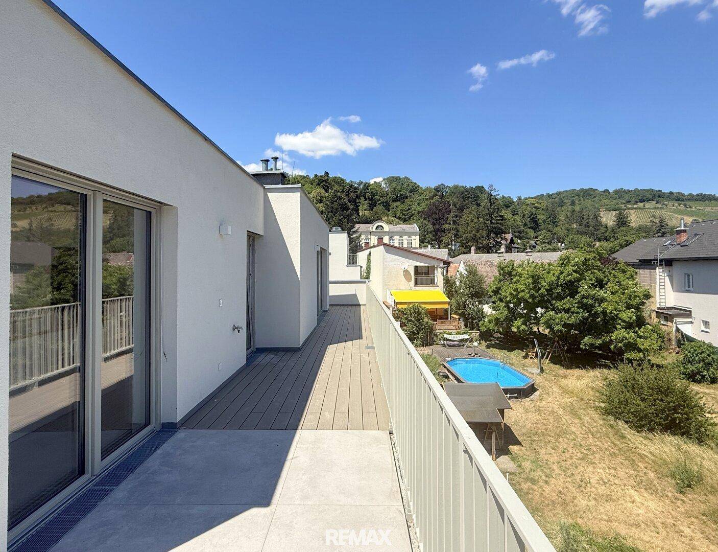 Große Terrasse mit Blick auf einen Pool und die umliegende Wohnbebauung.