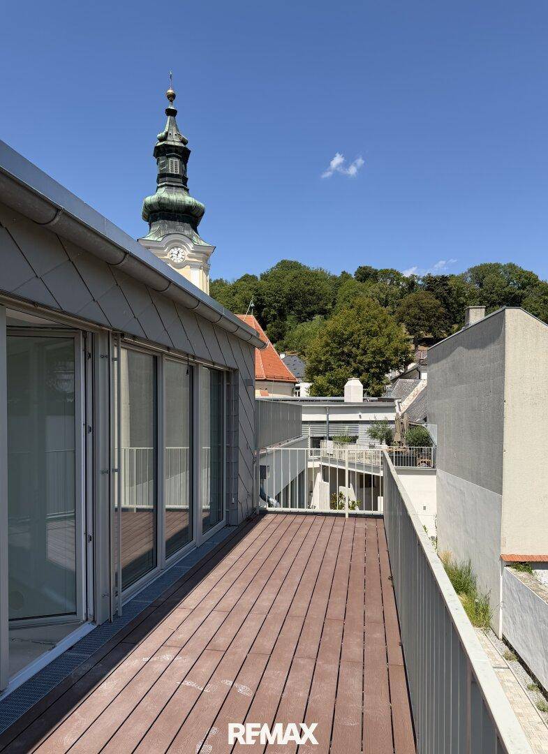 Geräumiger Balkon mit Holzboden und Blick auf die historische Kirche und die Landschaft.