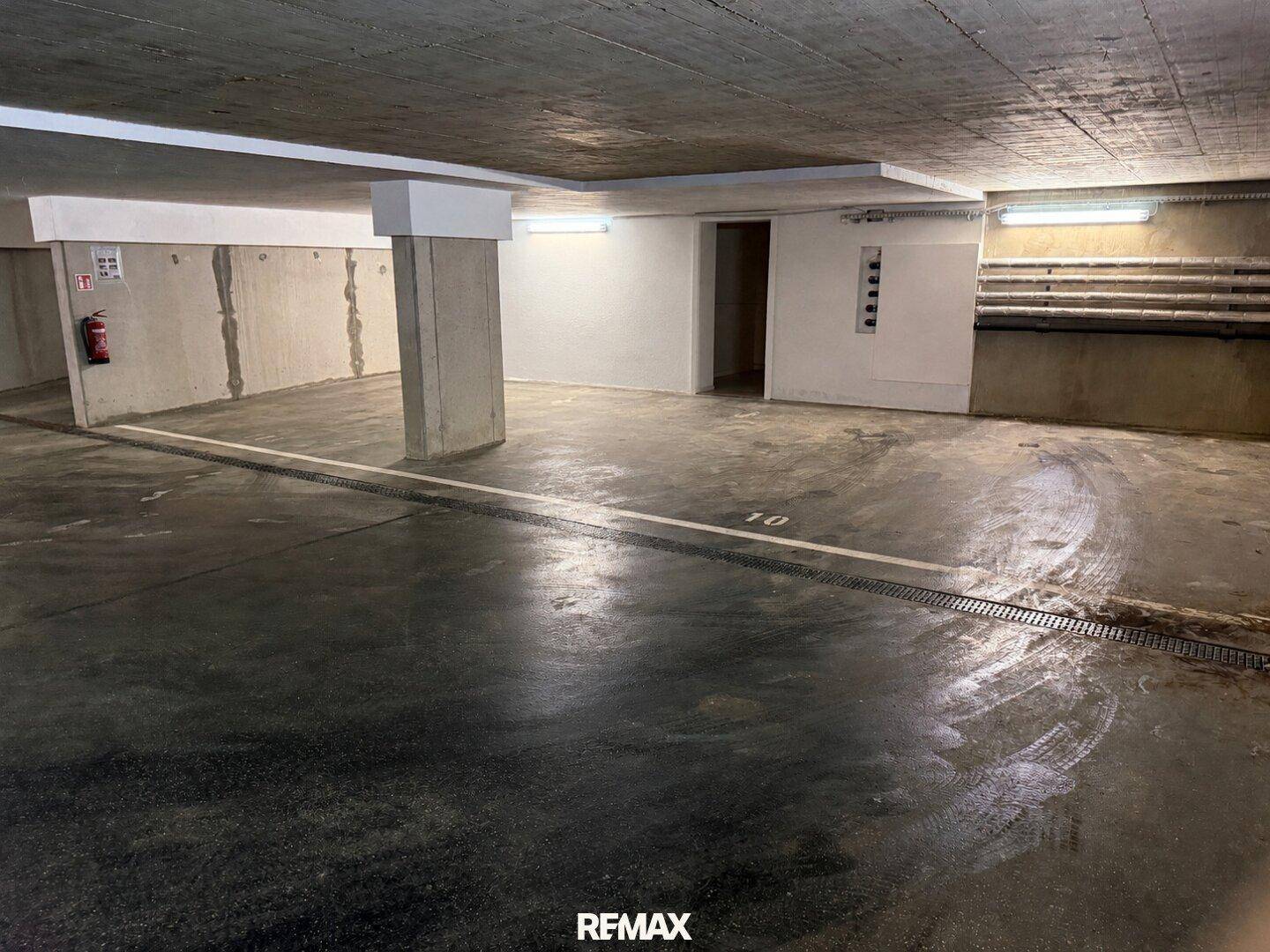 Tiefgarage mit mehreren Stellplätzen und Betonwänden, gut beleuchtet.