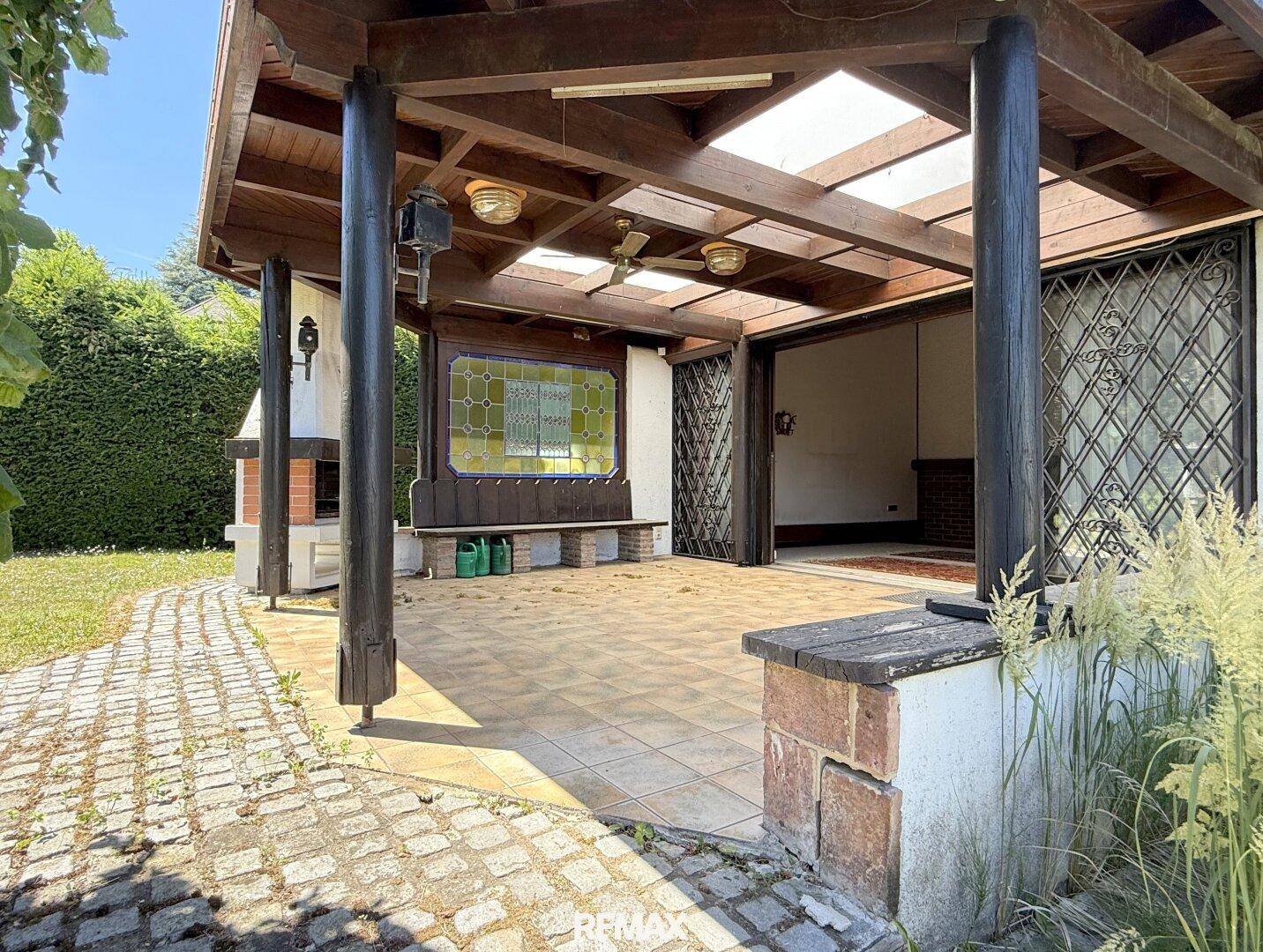 Geräumige überdachte Terrasse mit Fliesenboden und direktem Zugang zum Garten.